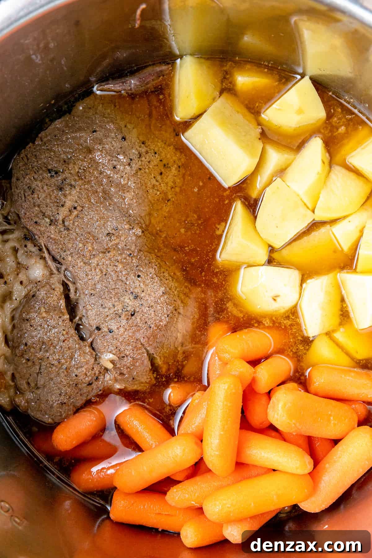 Chuck roast with carrots and potatoes simmering in beef broth in the Instant Pot.