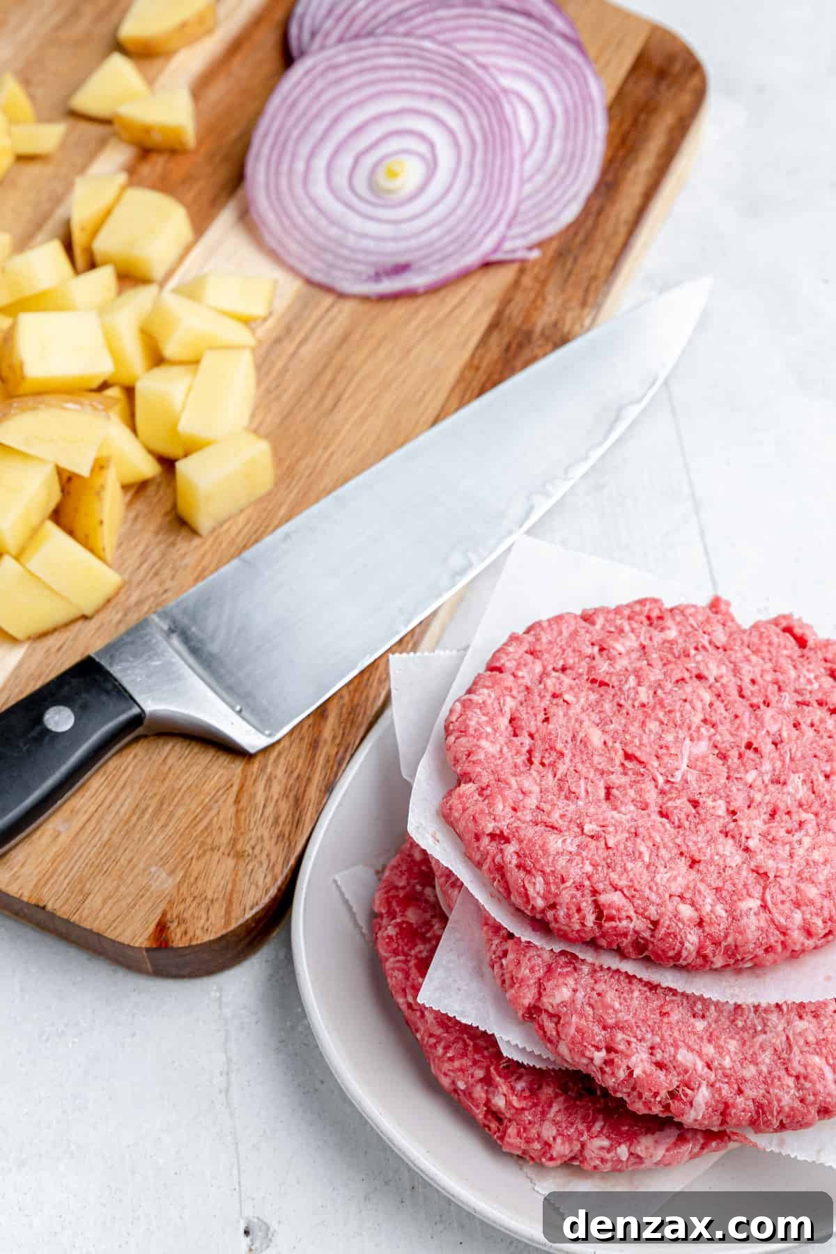 A beef patty, diced potatoes, onions and a knife