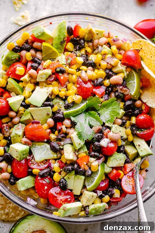 Close-up overhead shot of a colorful bowl of Cowboy Caviar, showcasing fresh ingredients like corn, beans, avocado, and tomatoes.