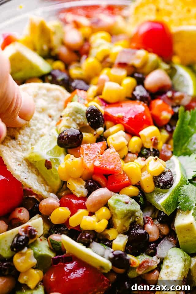 Scooping up vibrant Cowboy Caviar with a crunchy tortilla chip, showing the perfect texture and mix of ingredients.