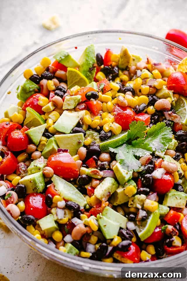 A vibrant bowl of Cowboy Caviar, featuring a colorful mix of avocado, corn, tomatoes, black-eyed peas, beans, and cilantro, ready to be enjoyed.