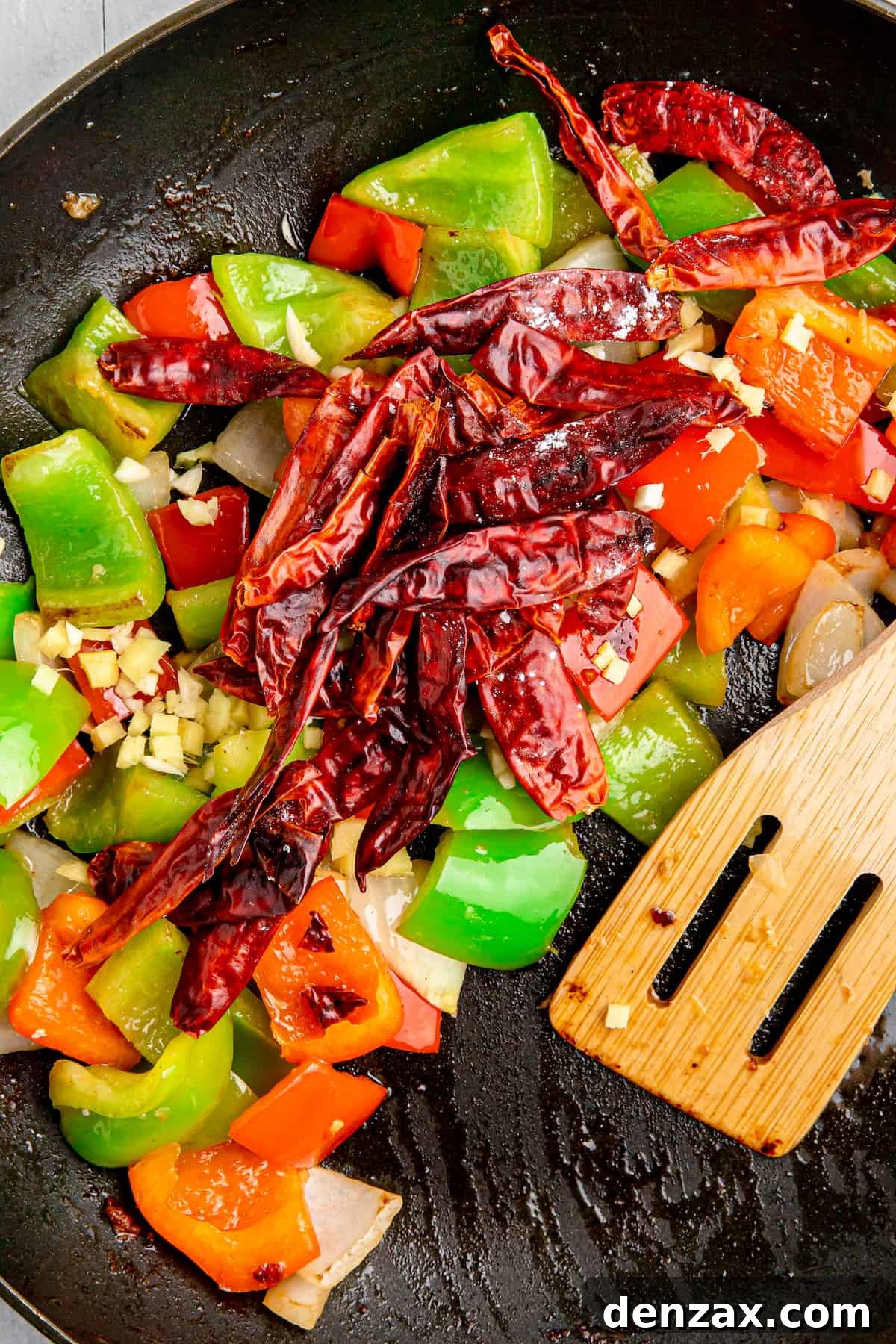 Chopped vegetables and dried chilies are sauteed in a pan for Szechuan Chicken.