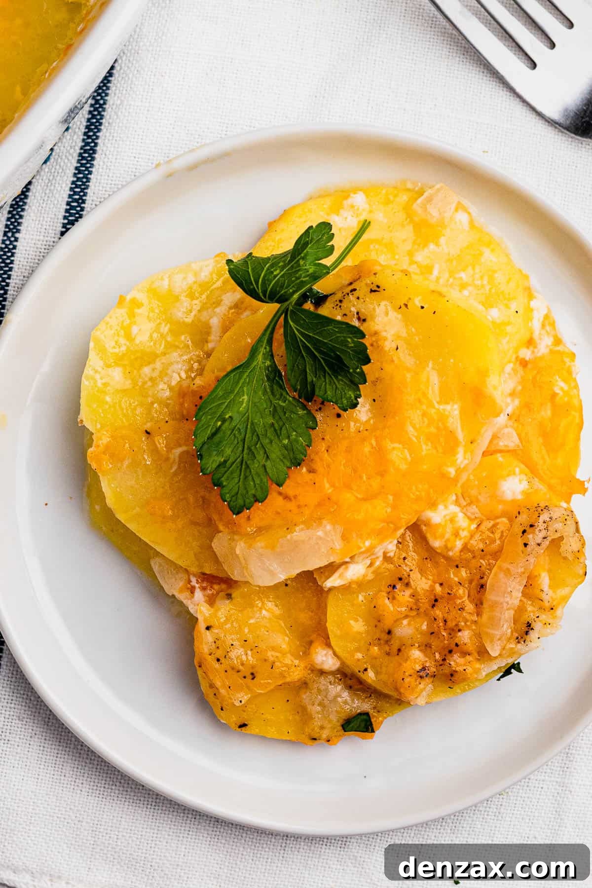 A small dish with a serving of cheesy sliced potatoes.