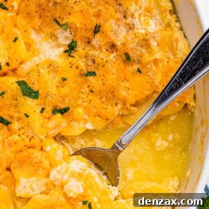 scalloped potatoes in a white casserole dish with a spoon inside the dish