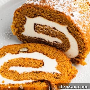 Pumpkin cake roll with one slice cut out and the filling exposed.
