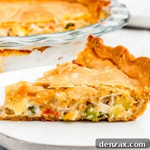 A baked chicken pot pie with a slice removed, resting on a plate with a fork.