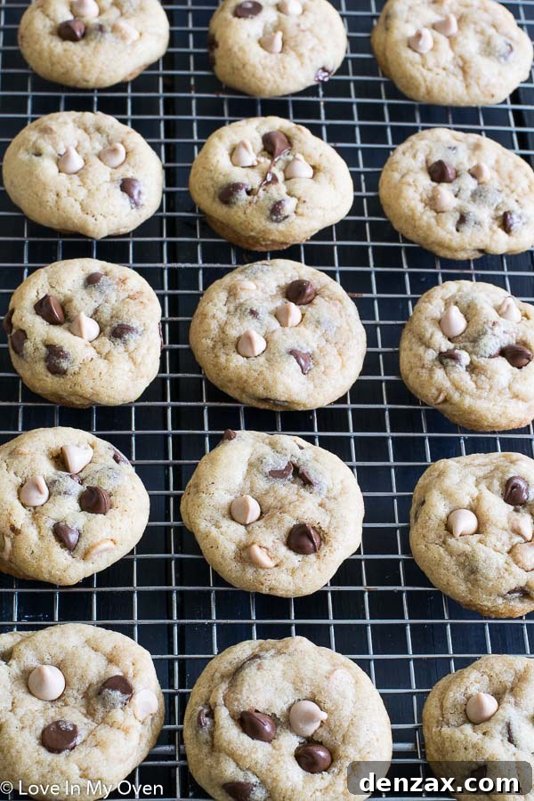 Perfectly baked sea salt caramel chocolate chip cookies cooling on a wire rack, with some in the background on a baking sheet