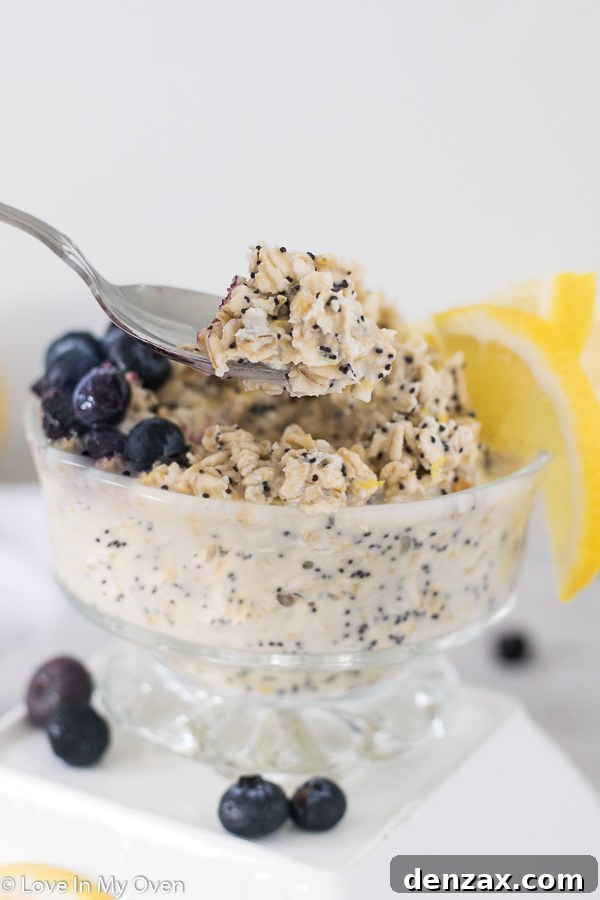 Close-up of a jar of lemon poppy seed overnight oats with a spoon, highlighting the creamy texture and poppy seeds.