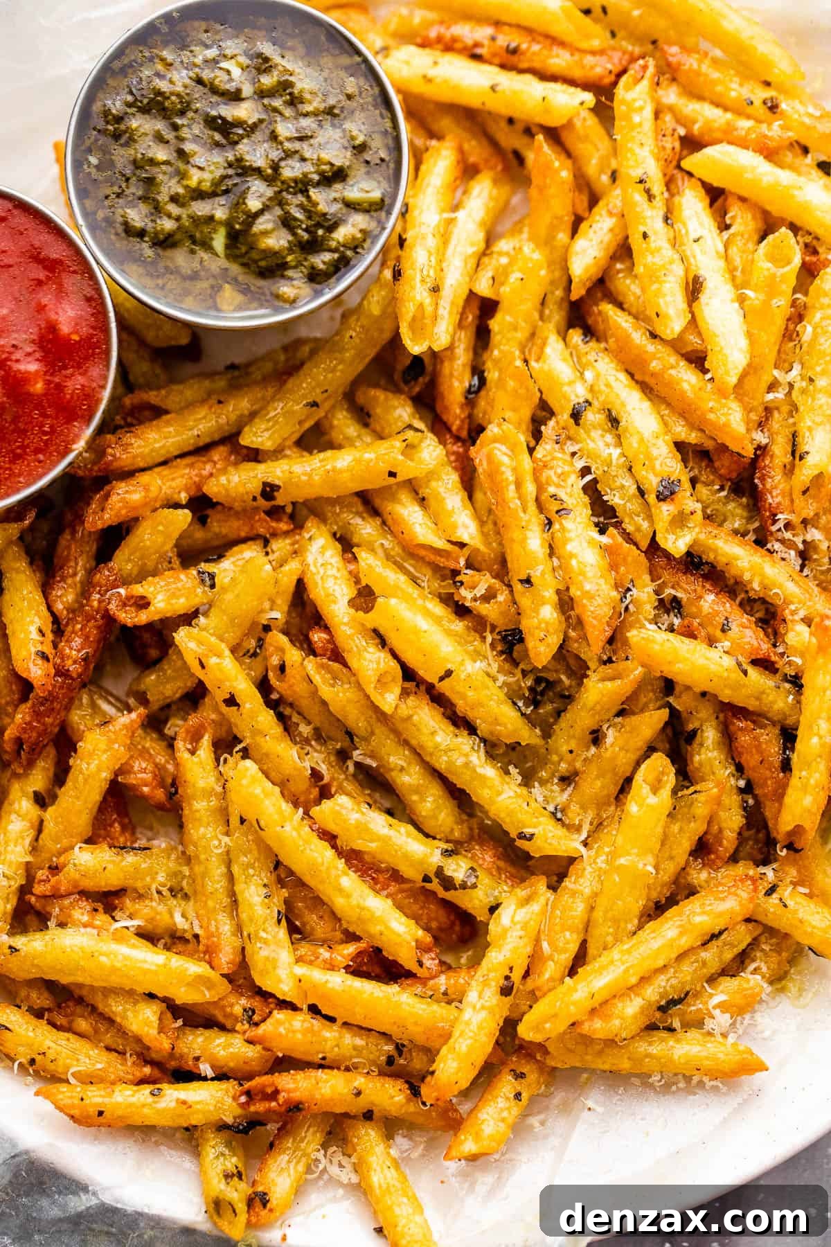 plate with baked pasta chips served with a side of basil pesto and marinara sauce