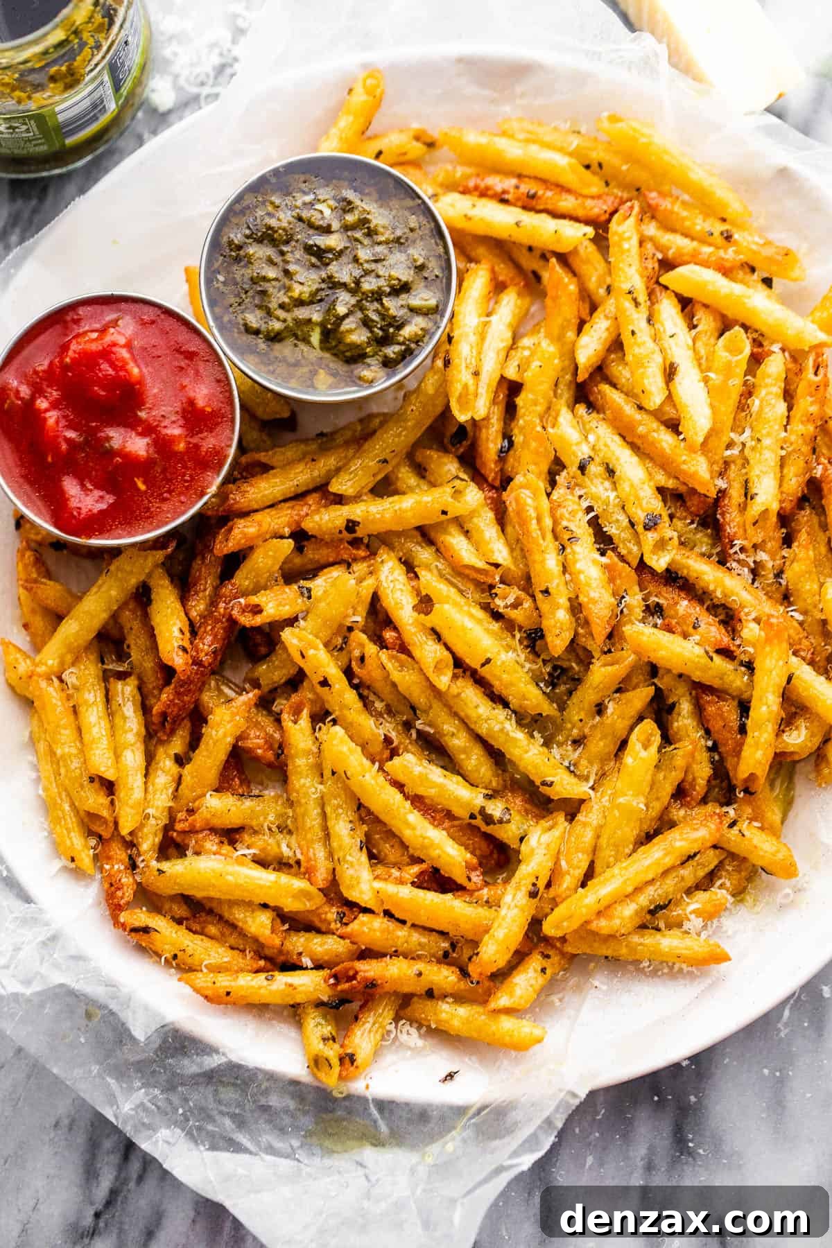 plate with baked pasta chips served with a side of basil pesto and marinara sauce