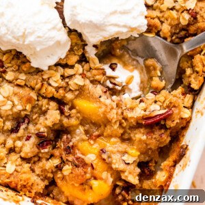 peach crisp in a white baking dish topped with three scoops of vanilla ice cream