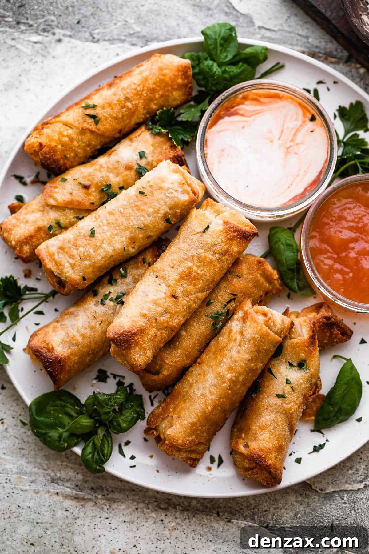 A plate of golden brown, crispy spring rolls arranged neatly, with a small bowl of dipping sauce beside them.