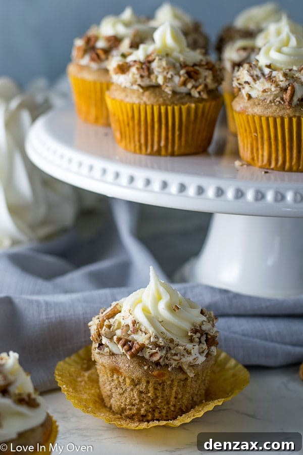 A trio of perfectly baked carrot cake cupcakes on a rustic wooden surface, highlighting their soft texture.