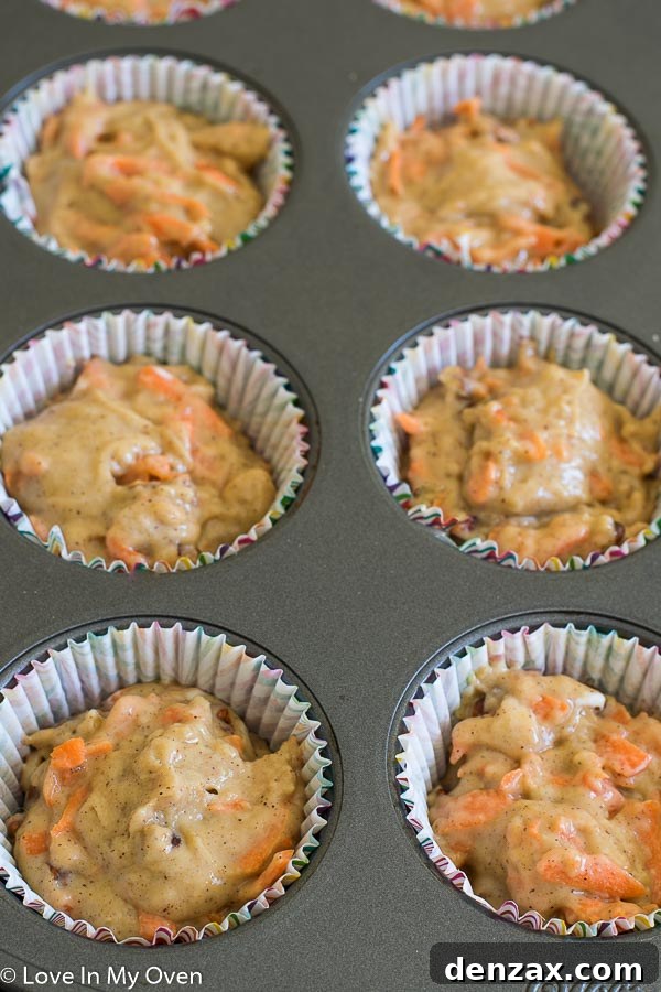 Two hands reaching for a perfectly frosted carrot cake cupcake, emphasizing its inviting appeal.