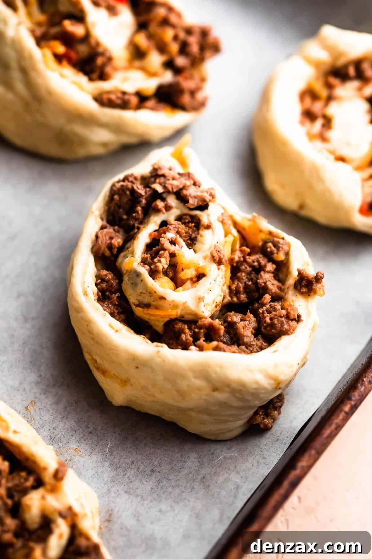 The rolled pizza dough filled with ground beef and cheese, already cut into individual pinwheels before baking.