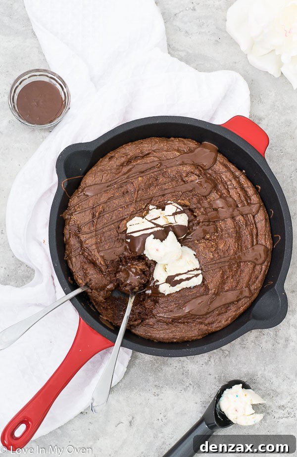 Close-up of a gluten-free skillet brownie, showcasing its fudgy texture, garnished with ice cream and caramel.