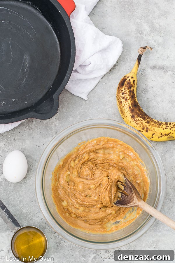 The smooth, thick brownie batter spread evenly in a cast iron skillet, ready for baking.