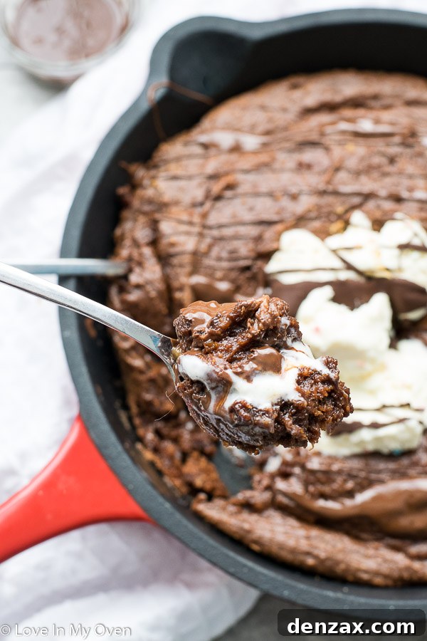 Overhead shot of the gluten-free skillet brownie, topped with melting vanilla ice cream and caramel sauce.