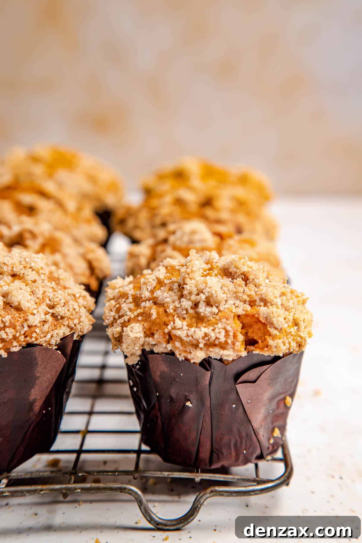 Freshly baked pumpkin muffins, rich with crumble topping, cooling on a wire rack, allowing air to circulate for perfect texture.