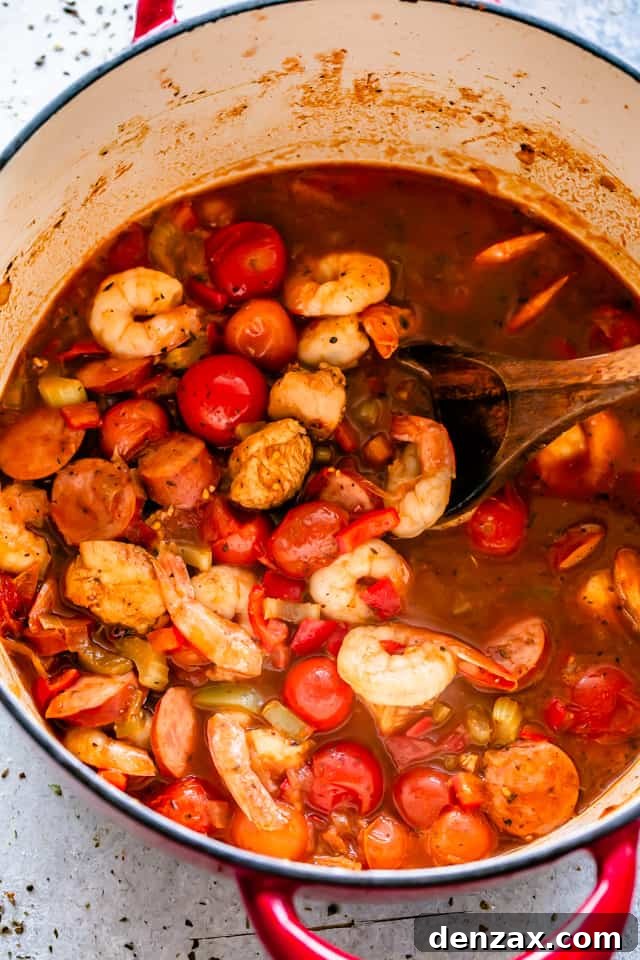 Shrimp, chicken, and sausage are cooking together in a large pot, mingling their flavors in the rich Cajun sauce.