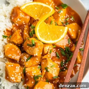 Overhead shot of orange chickn on a plate, garnished with an orange twist.