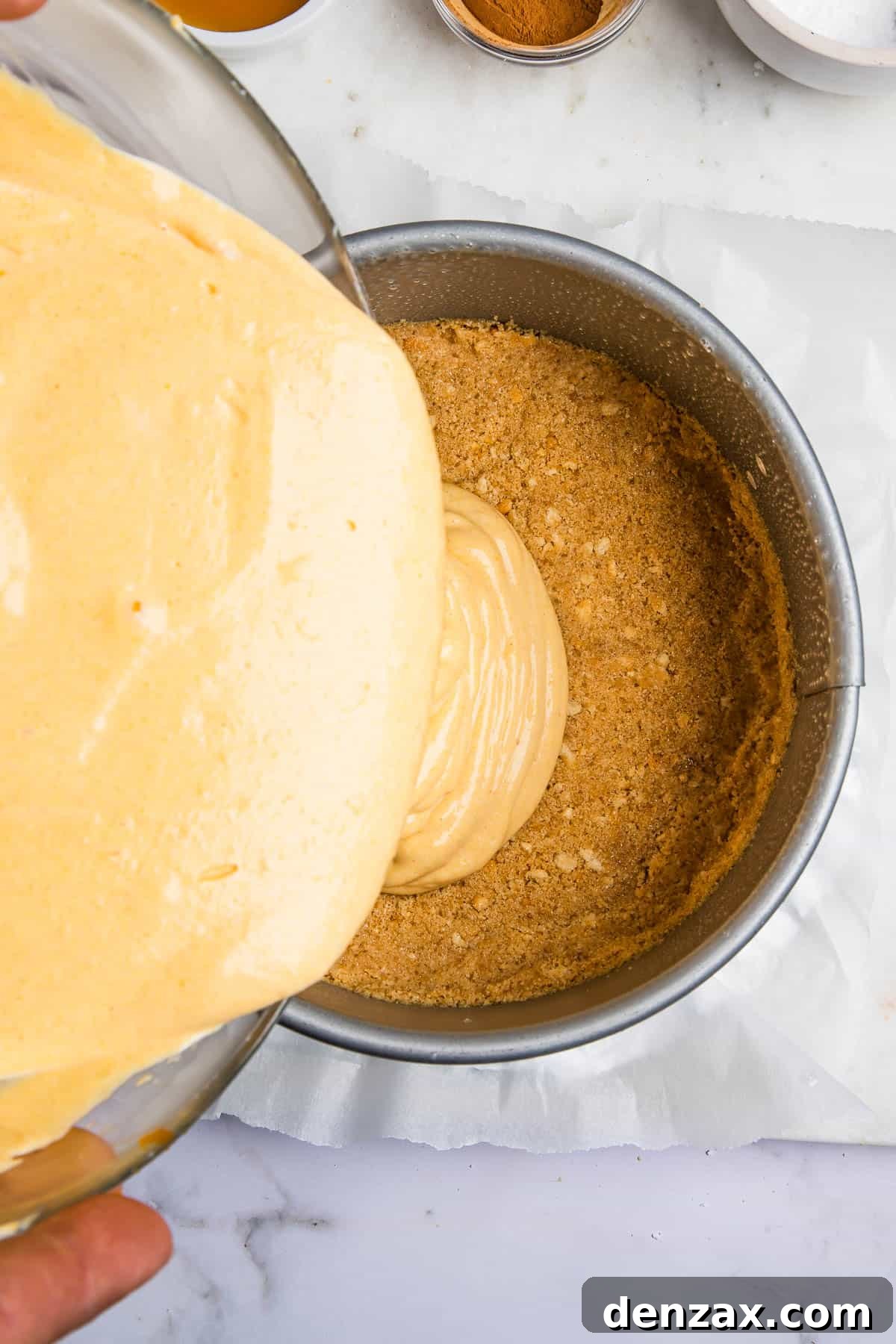 pouring cheesecake batter over crust inside of an instant pot.