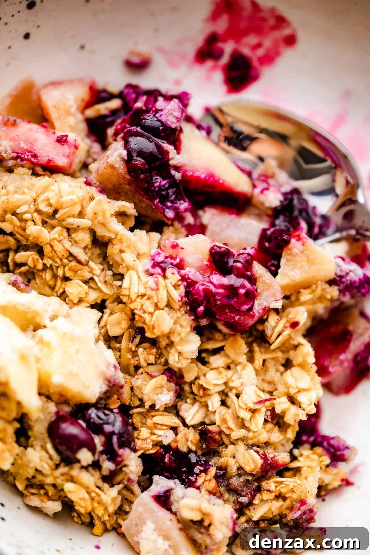a scoop of apples and berries baked oatmeal served on a white plate.