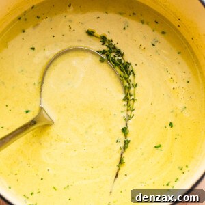 cream of asparagus soup in a pot with a ladle inside it.