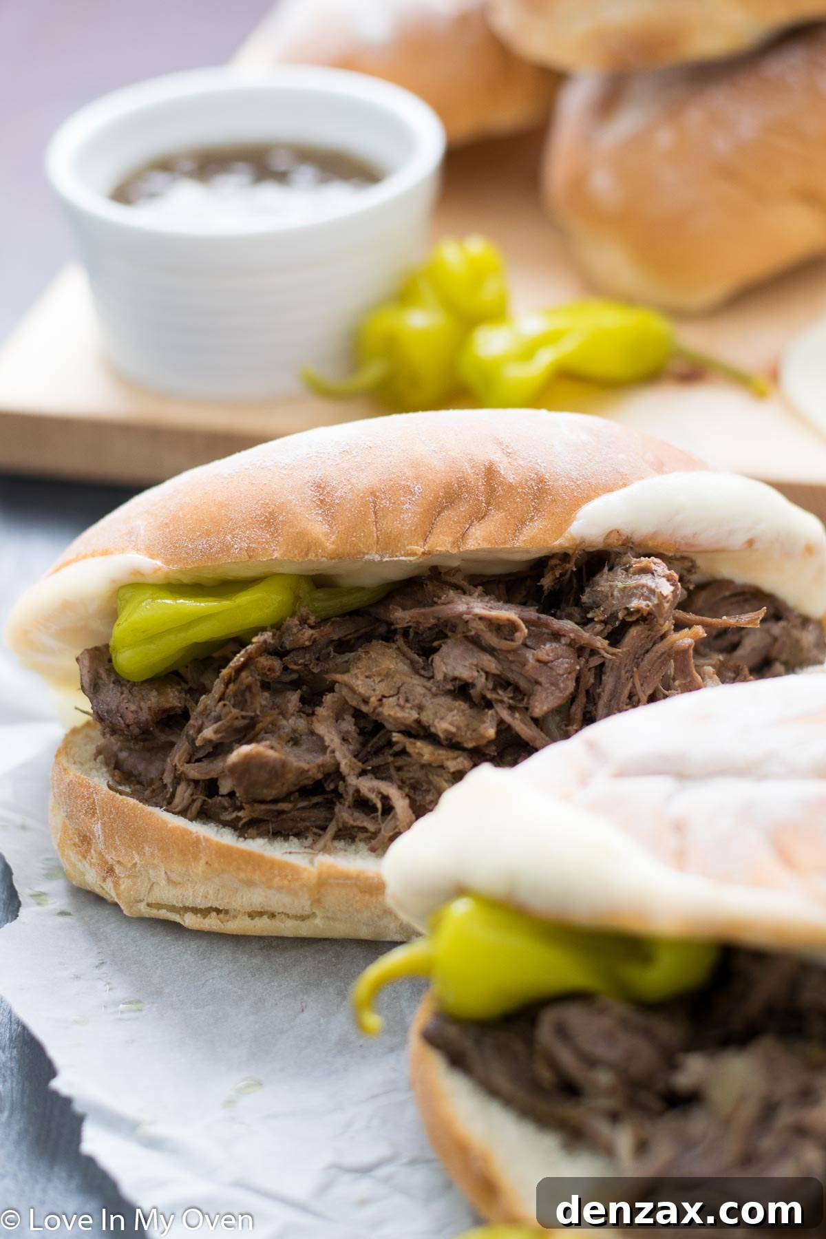Tender slow cooker Italian beef piled high on a hoagie roll with melted cheese, ready for dipping.