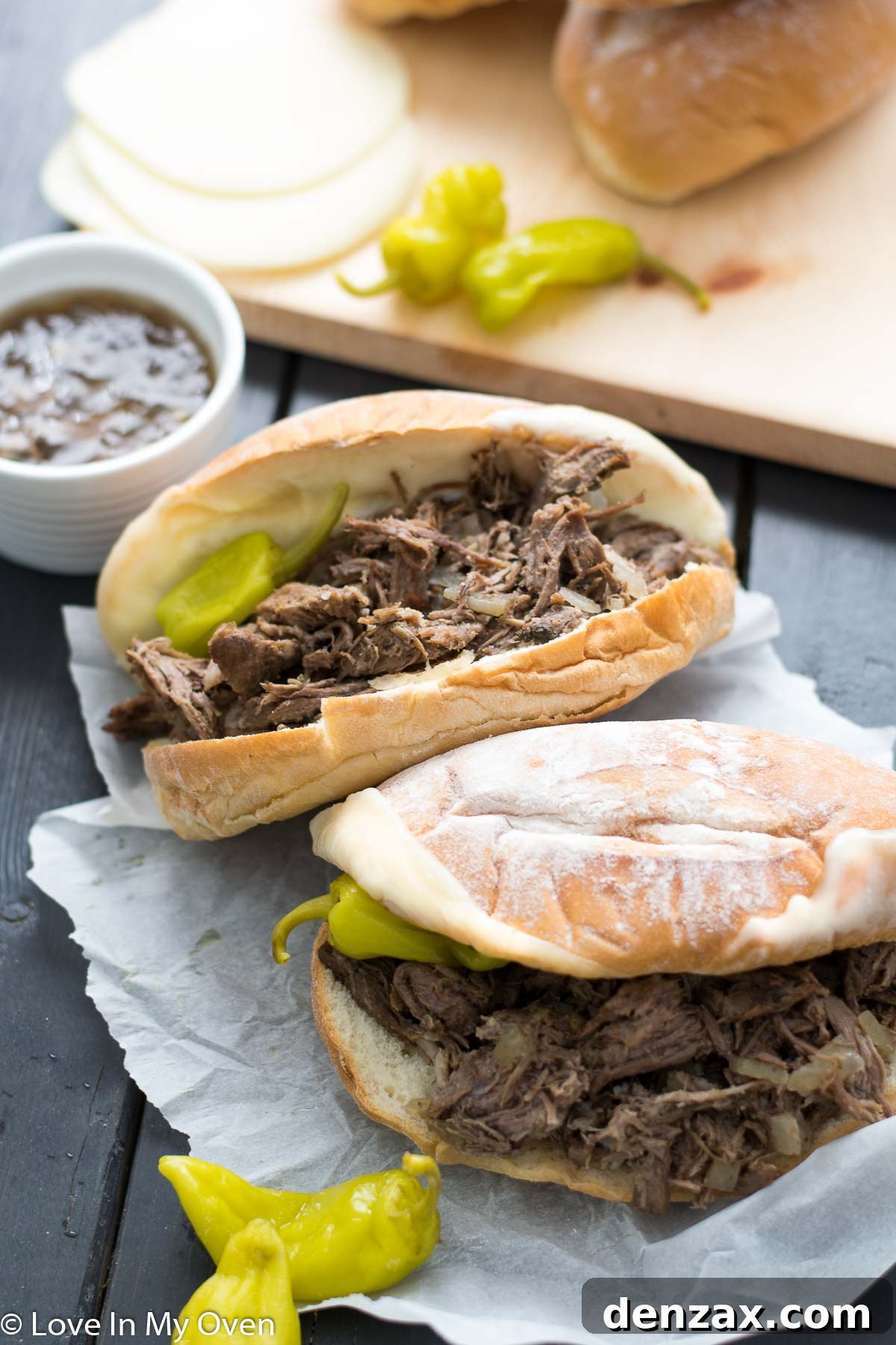 A serving of slow cooker Italian beef sandwich on a toasted roll with melted cheese, ready to be dipped in au jus.