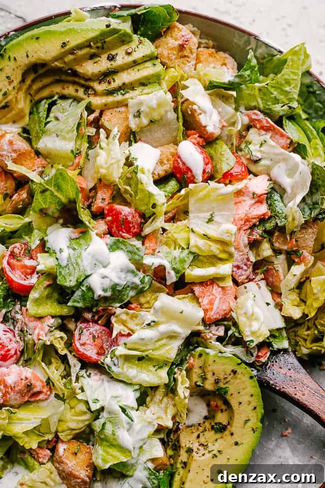 Salmon BLT Salad plated and tossed in creamy dressing, showcasing a vibrant and appealing meal.