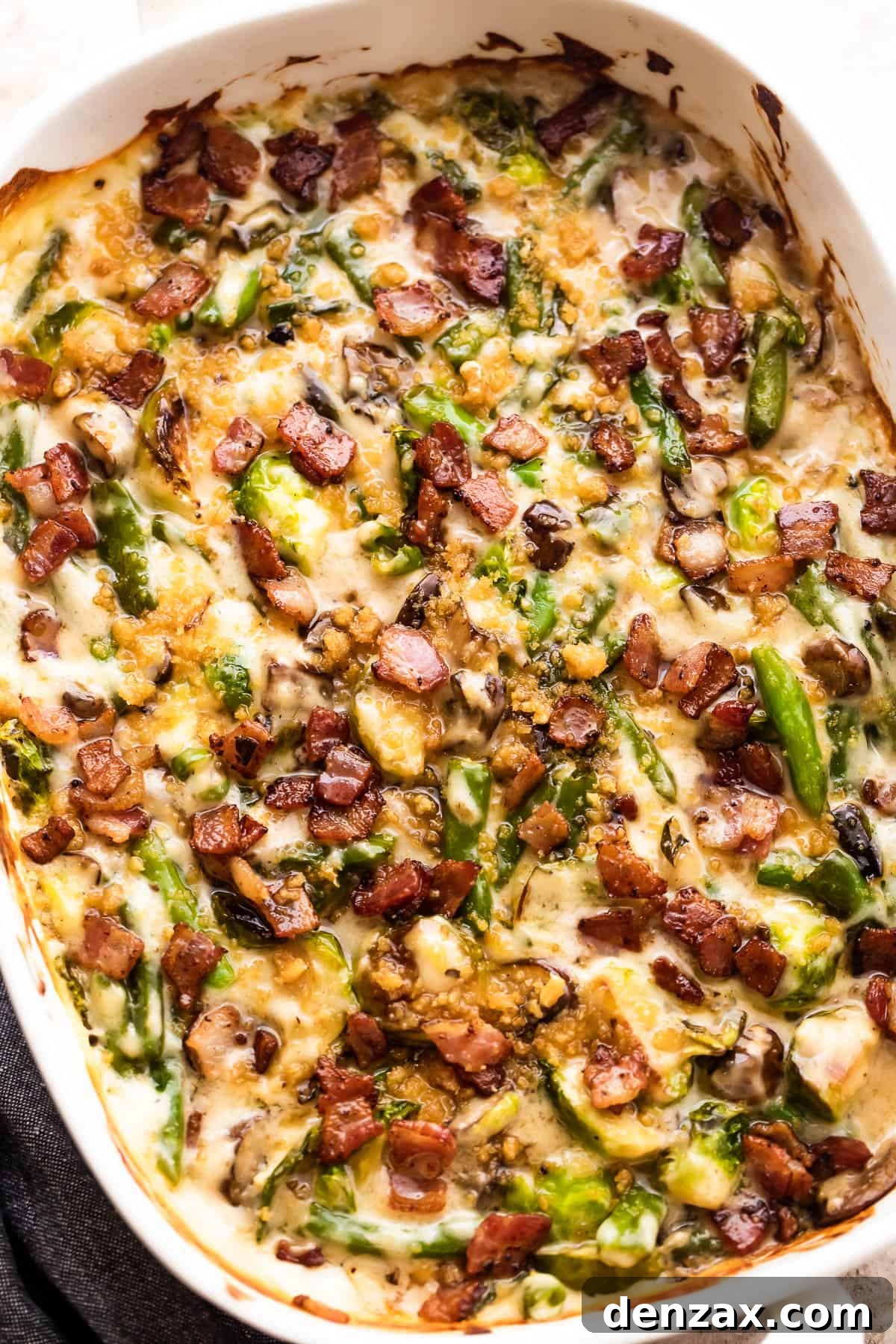 An overhead view of the finished green bean and Brussels sprouts casserole, generously topped with crispy diced bacon and golden breadcrumbs.