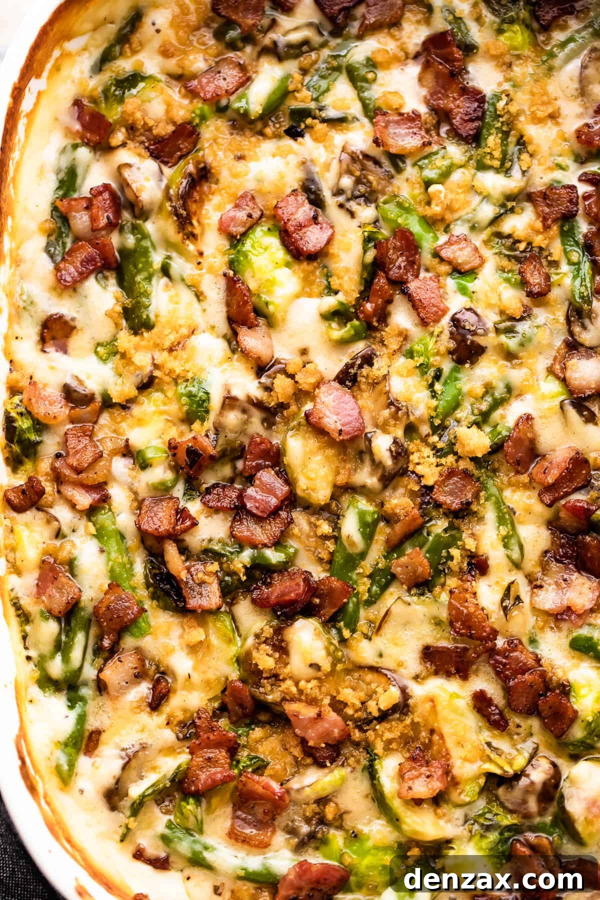 A close-up of the cooked green bean casserole, generously topped with glistening, crispy diced bacon and a golden-brown crust.