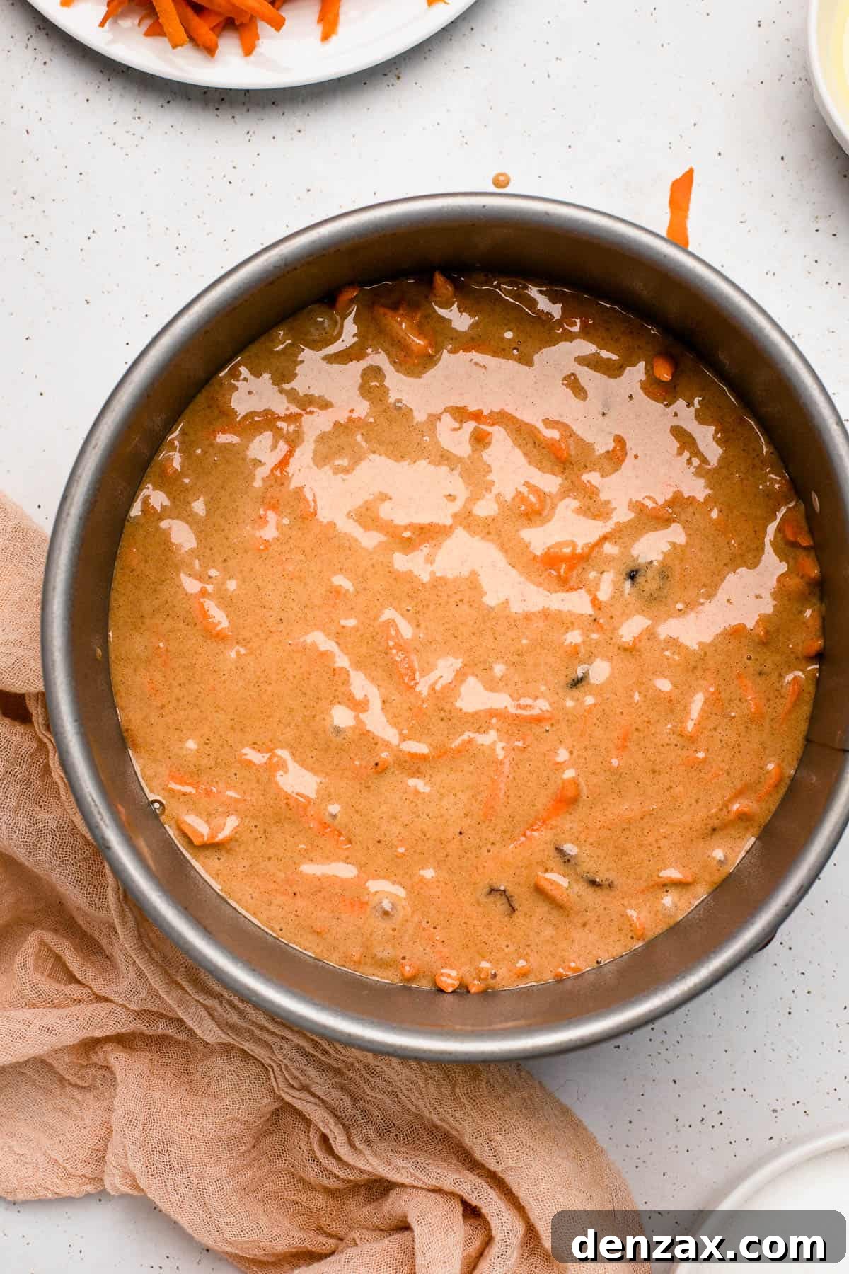 Overhead shot of rich carrot cake batter in a springform pan, ready for baking.