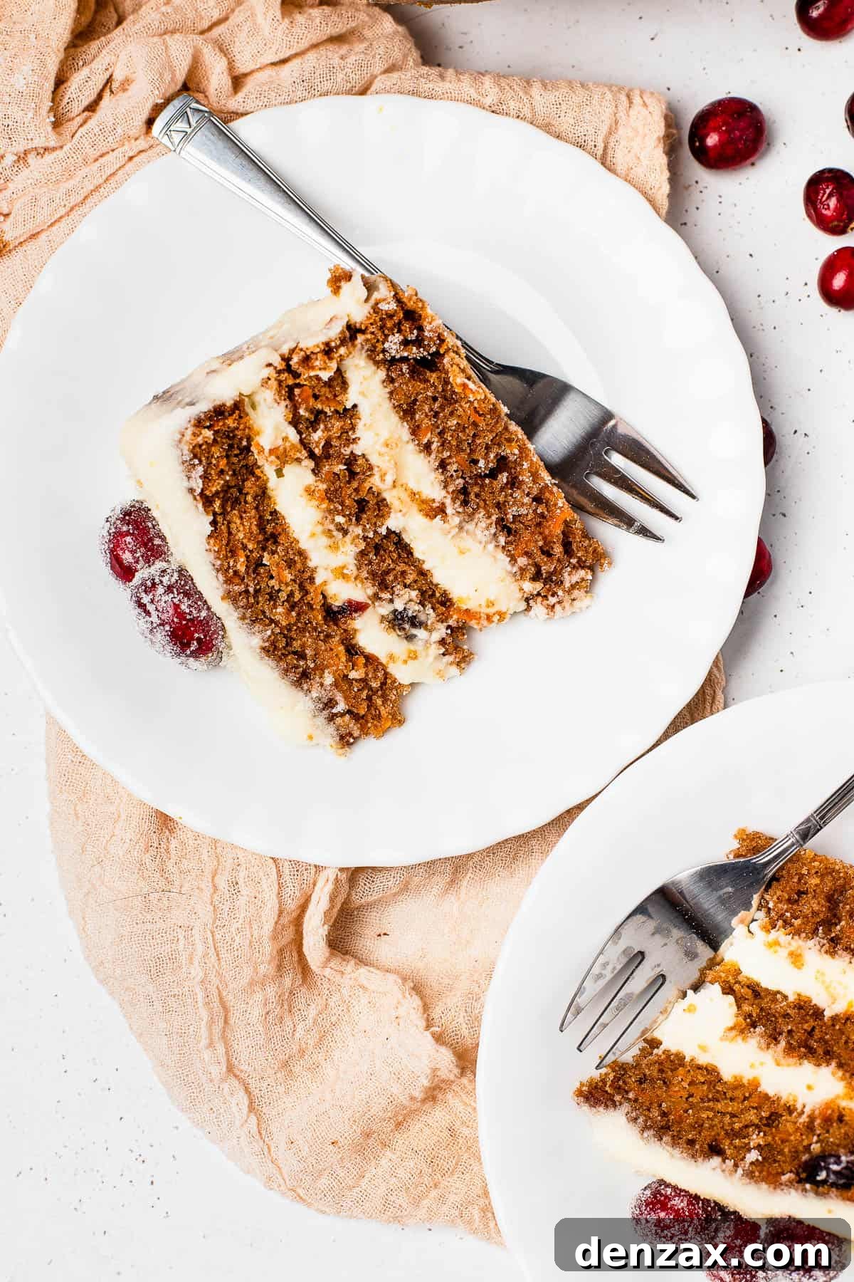 A close-up shot of a perfect slice of cranberry carrot layer cake on a dessert plate with a fork, showing the moist layers and frosting.