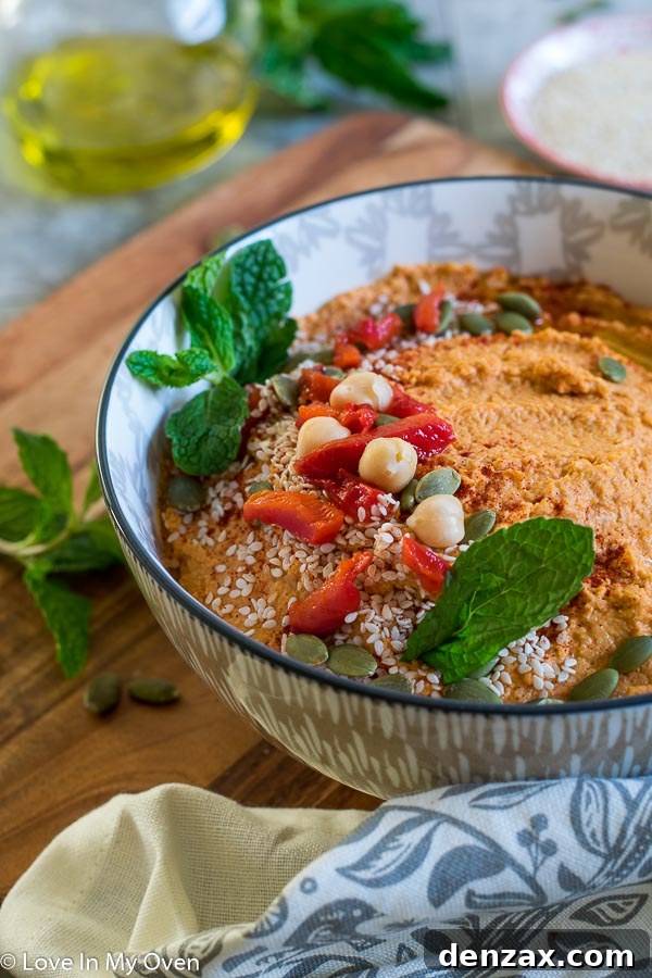 Serving bowl of spicy roasted red pepper hummus garnished with olive oil and paprika