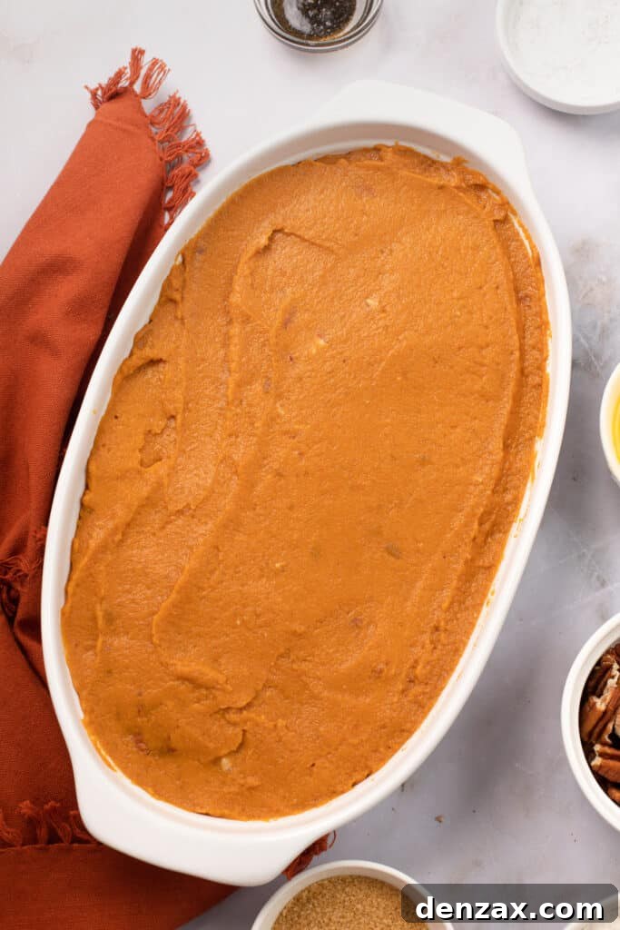 A baking dish containing the unbaked, creamy sweet potato casserole mixture, evenly spread and ready for its topping.