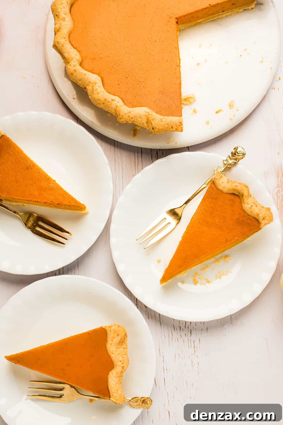 A perfectly baked pumpkin pie in a white serving platter, with one slice elegantly cut and placed on a dessert plate alongside a golden fork, inviting indulgence.