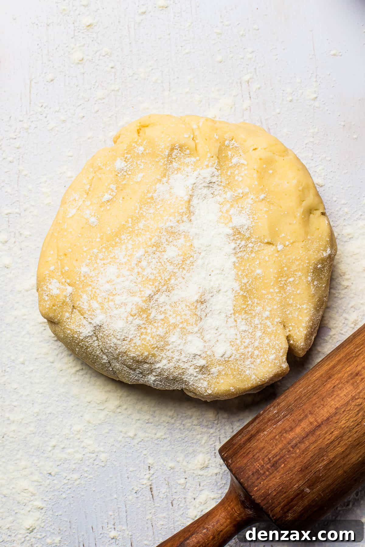 Freshly prepared pie dough, rolled out on a floured surface, with a rolling pin beside it, ready for placement in the pie dish.