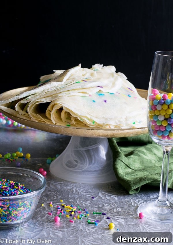 Funfetti Crepe Cake slice on a white plate with fresh berries