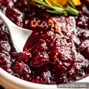 Homemade cranberry sauce in a bowl, garnished with rosemary and orange slices