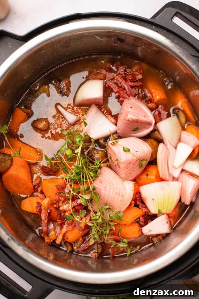 Overhead shot of onions, chicken thyme, and carrots in red wine sauce.