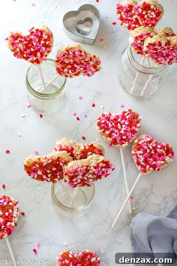 Heart-shaped Rice Krispie treats decorated with pink frosting and sprinkles, perfect for Valentine's Day celebrations.