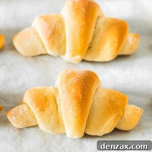 A row of crescent rolls on a parchment-lined baking sheet.