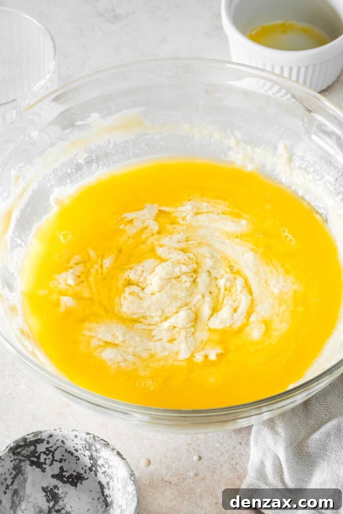 A mixing bowl with dough and melted butter inside.