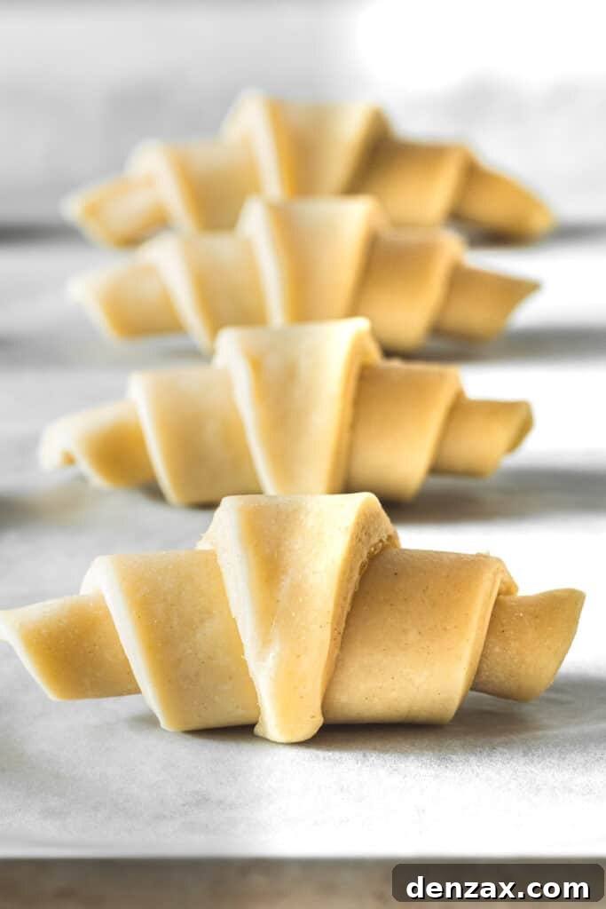 Raw dough rolled into crescents on a baking sheet.