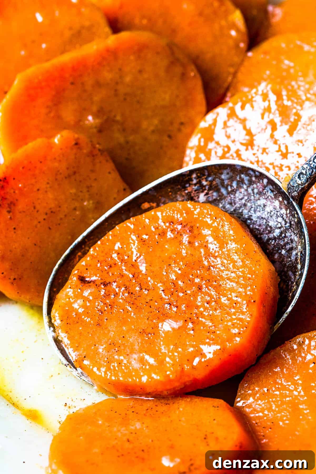 Candied yam slices with a serving spoon scooping up one of the slices.