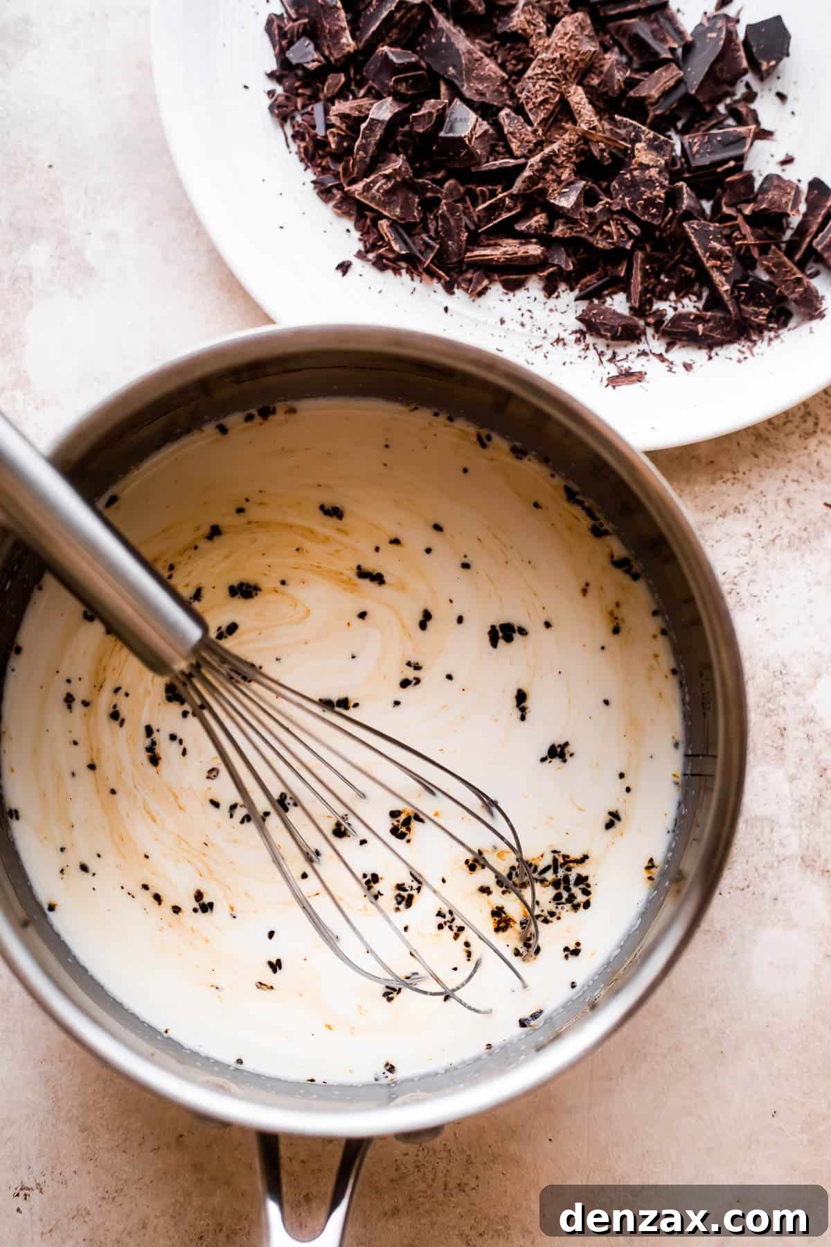 overhead shot of a saucepan filled with heavy cream and a plate with chopped chocolate placed nearby.