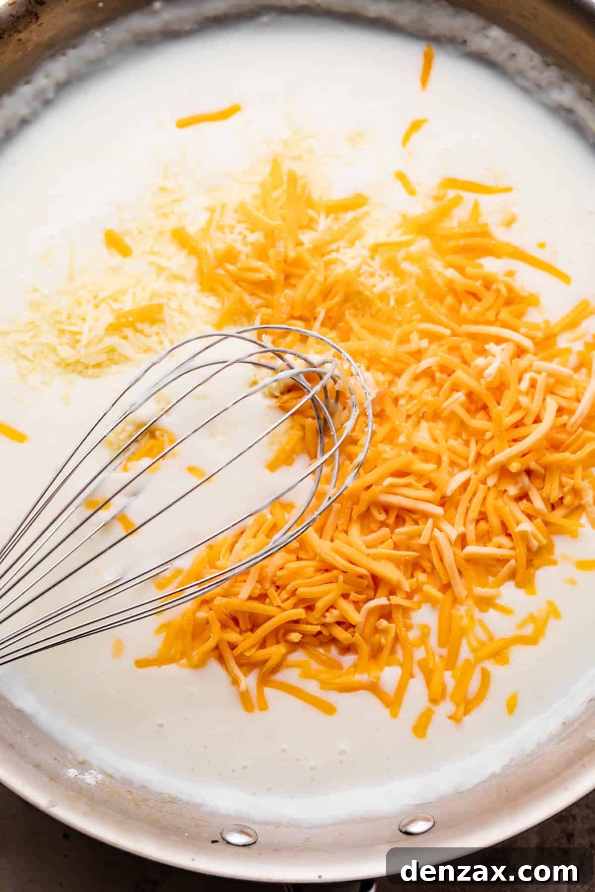 whisking shredded cheddar cheese with milk.
