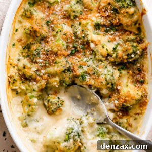 overhead shot of an oval baking dish with Cheesy Broccoli Casserole and a spoon mixing through it.